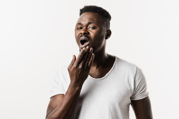 L'uomo afroamericano sente mal di denti, dolore e disagio del dente Uomo africano con infezione da carie o lesioni al dente o alle gengive su sfondo bianco