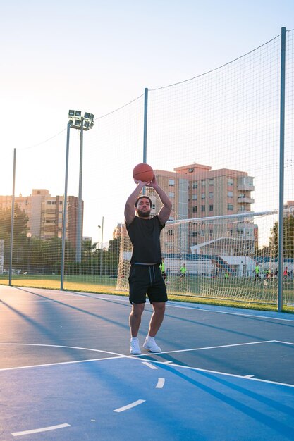 L'uomo afrolatino lancia una palla nel canestro sul campo da basket