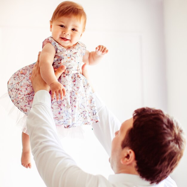 L&#39;uomo alza la sua bambina in abito elegante con i fiori