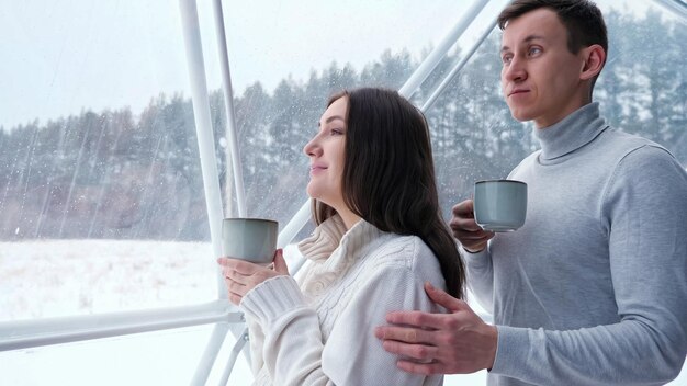 L'uomo animali domestici donna sulla spalla gustando un drink a casa in inverno