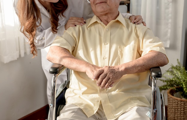 L'uomo anziano asiatico era malato e seduto sulla sedia a rotelle. Il medico controlla a casa lo stato di salute dell'età pensionabile.