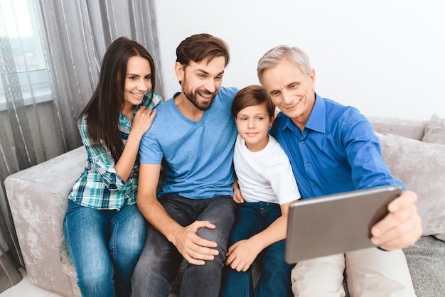 L'uomo anziano è fotografato sul tablet con la famiglia a casa.
