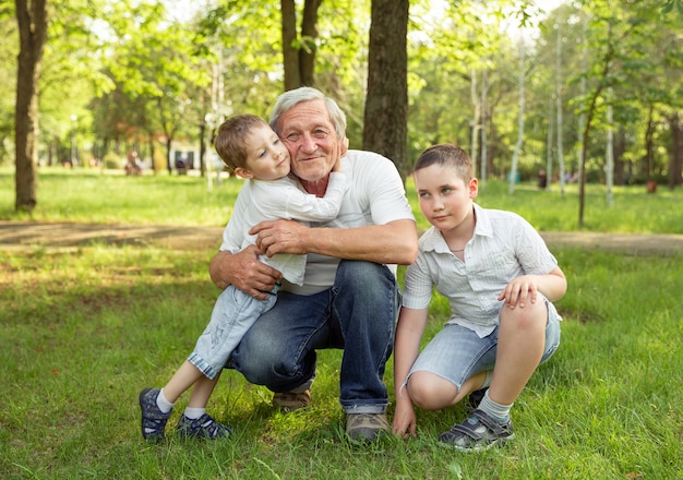 L'uomo anziano ed i nipoti stanno abbracciando e sorridendo, riposando insieme