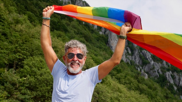 L'uomo anziano Gay dai capelli grigi tiene la bandiera LGBT