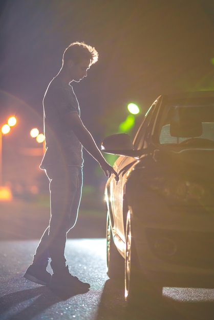 L'uomo apre l'auto sulla strada. sera notte