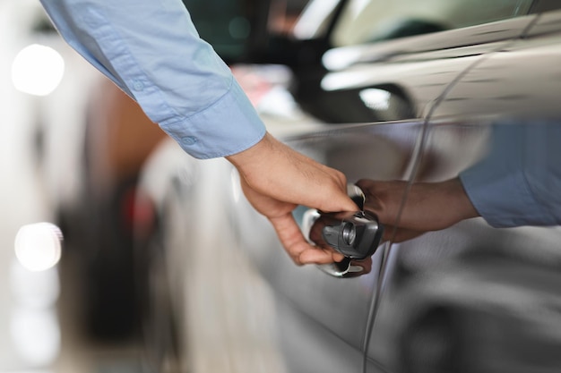 L'uomo apre la portiera dell'auto facendo un giro di prova allo showroom ritagliata