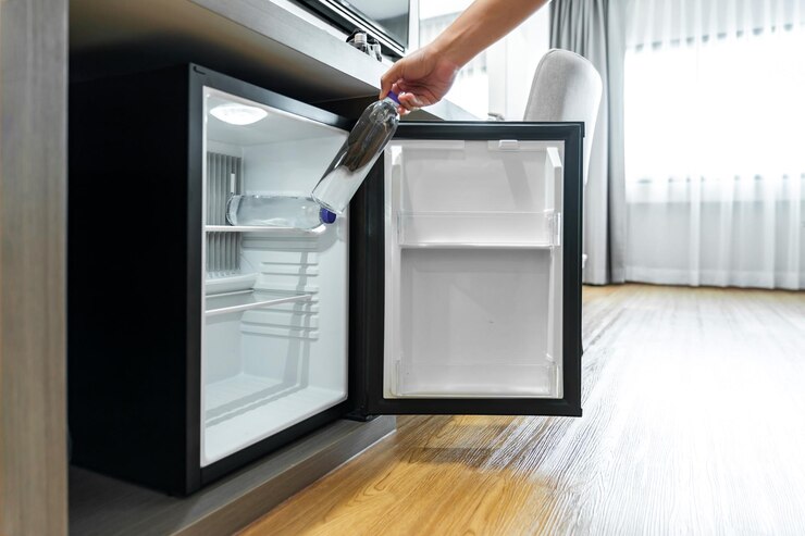 L'uomo aprì con la mano un piccolo frigorifero e raggiunse una bottiglia di acqua di plastica da bere sotto il bancone di legno nella camera da letto dell'hotel.