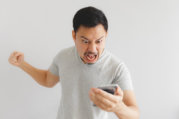 L&#39;uomo arrabbiato in maglietta grigia si arrabbia con lo smartphone.