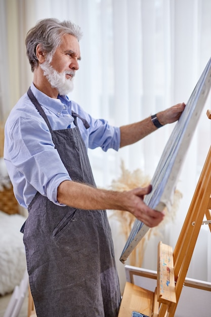 L'uomo artista guarda la tela il suo capolavoro, sta pensando, contemplando, divertendosi a disegnare, dipingere