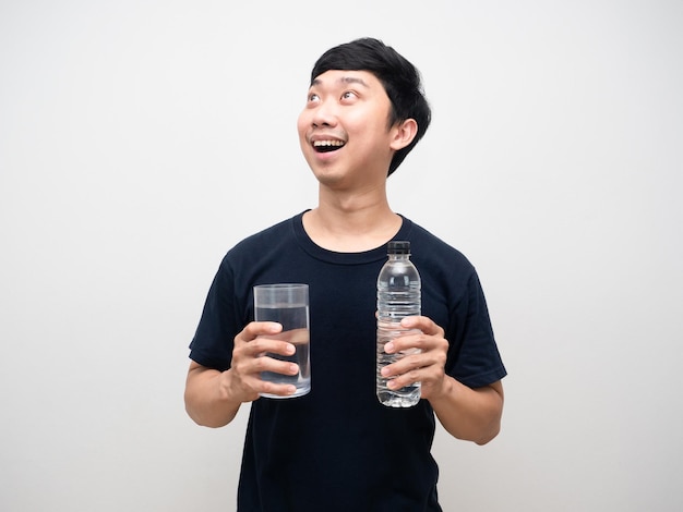 L'uomo asiatico che tiene il bicchiere con una bottiglia d'acqua si sente eccitato guardando in alto