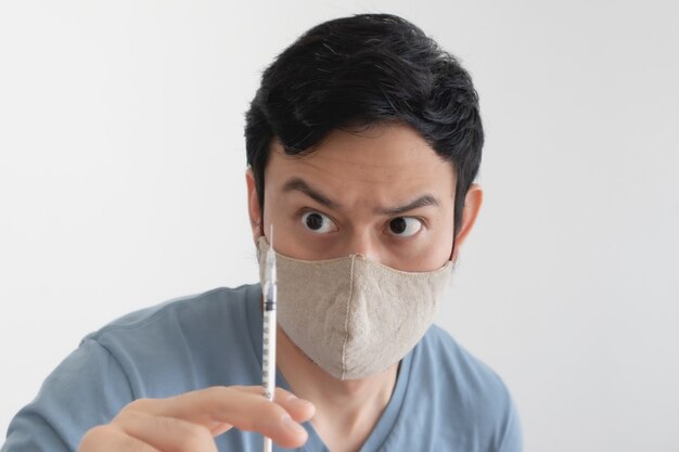 L'uomo asiatico con una maschera facciale sta iniettando un vaccino. Concetto di protezione antivirus.