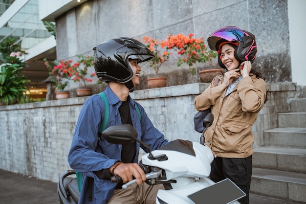 l'uomo asiatico su una moto prende una donna che indossa un casco sul lato della strada