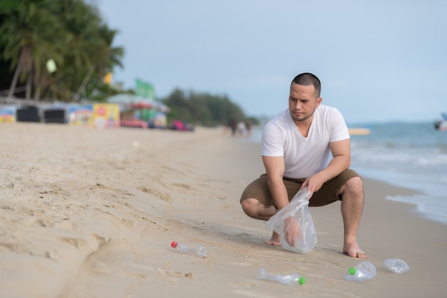 L'uomo asiatico tiene la spazzatura all'interno dei beachpeople del mare che si offre volontario tenendo la bottiglia di plastica della spazzatura