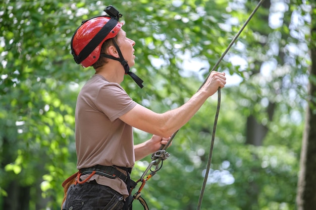 L'uomo assicura il suo compagno di cordata con un dispositivo di assicurazione e una corda Il manichino dell'alpinista che tiene l'attrezzatura per la sicurezza dell'alpinismo su roccia