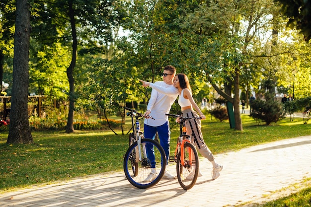 L'uomo attraente in occhiali da sole sta puntando il dito mostrando qualcosa alla donna concentrata