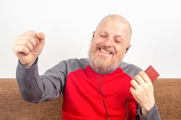 L'uomo barbuto ama ascoltare la sua musica preferita a casa con un lettore audio in piccole cuffie.