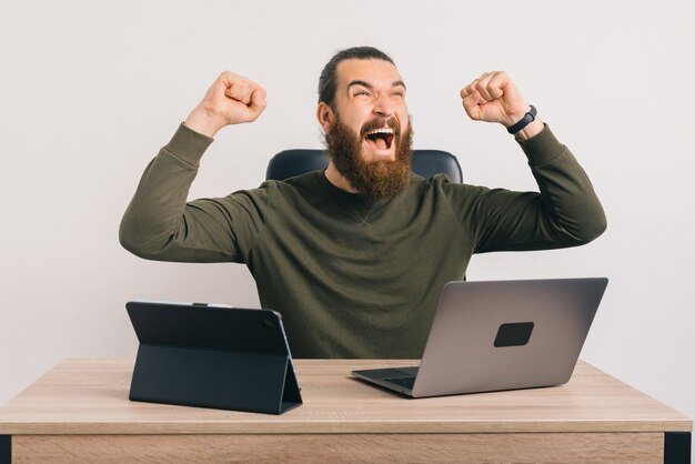 L'uomo barbuto bello è felice perché ha vinto qualcosa in ufficio.