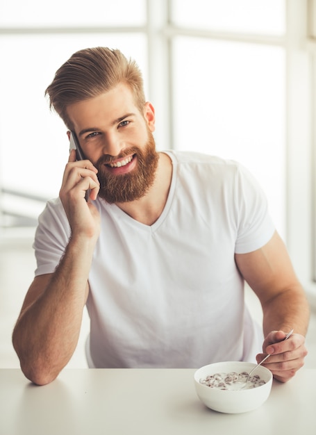 L'uomo barbuto bello sta parlando sul telefono cellulare.