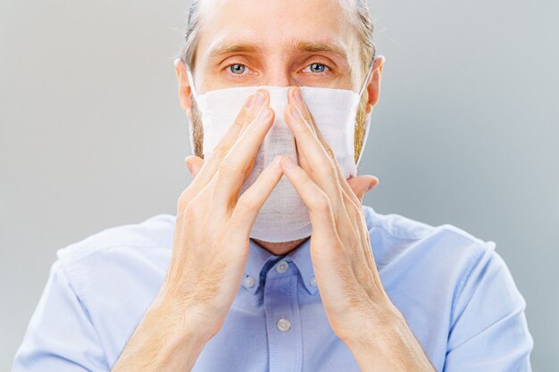 L'uomo barbuto bianco in camicia blu indossa una maschera dall'inquinamento atmosferico e dal coronavirus Covid-19.