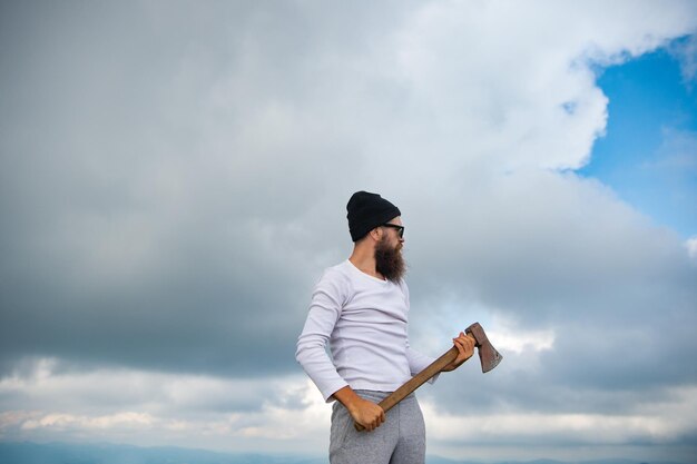 L'uomo barbuto boscaiolo con cappello ha l'ascia L'uomo barbuto boscaiolo con l'ascia