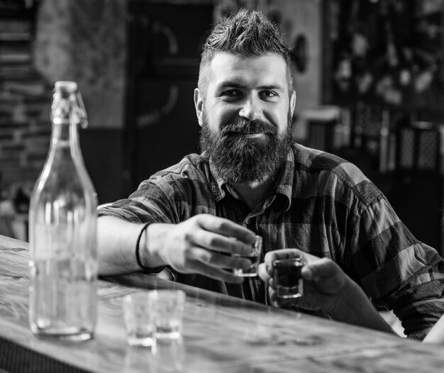 L'uomo barbuto brutale hipster trascorre il tempo libero con un amico al bancone del bar Uomini che si rilassano al bar Bevande alcoliche forti Venerdì relax al bar Amici che si rilassano nel bar pub Concetto di applausi Lasciati ubriacare