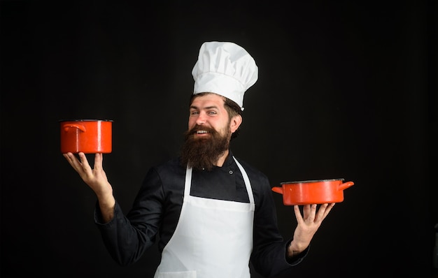 L'uomo barbuto cuoco indossa un cappello da chef e un cuoco professionista uniforme con un cappello da cuoco capo uomo in bianco