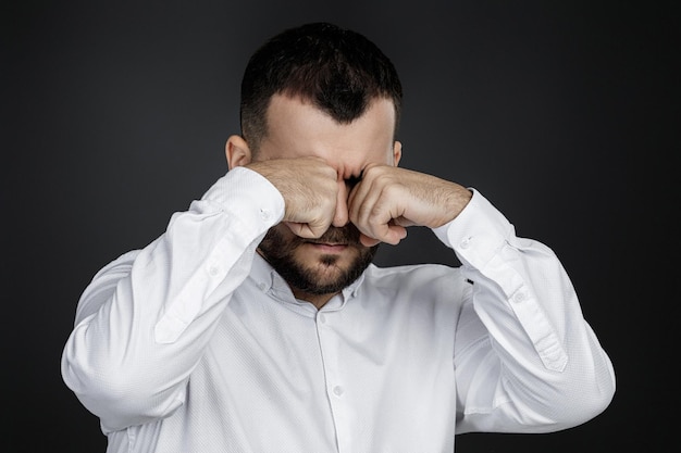 L'uomo barbuto divertente sta piangendo e asciugandosi le lacrime