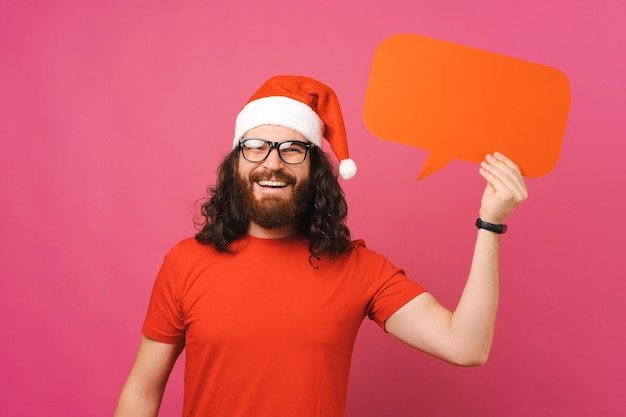 L'uomo barbuto fresco che indossa il cappello di Natale sta tenendo il discorso della bolla con un'idea