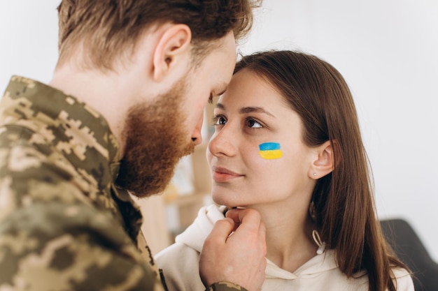 L'uomo barbuto militare della coppia ucraina in uniforme bacia la sua ragazza a casa