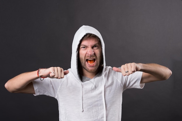 L'uomo barbuto mostra i pugni. L'uomo arrabbiato con la barba indossa il cappuccio. Modello di moda in maglietta con cappuccio. Stile di vita attivo e attività salutari. Stile di moda e concetto di tendenza.