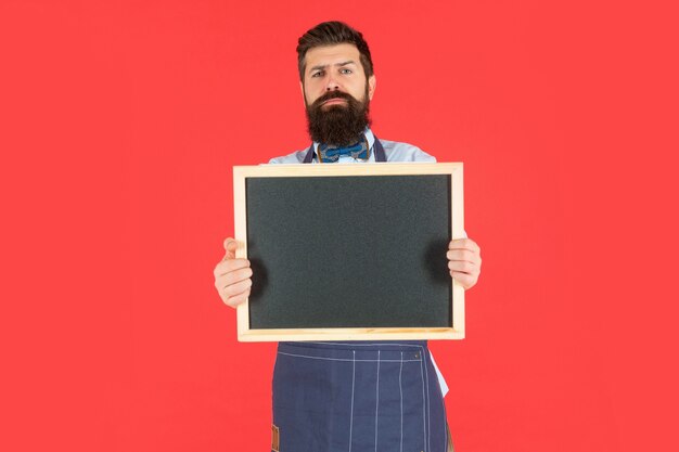 L'uomo barbuto serio tiene lo spazio della copia del fondo rosso della lavagna della scuola, back-to-school.