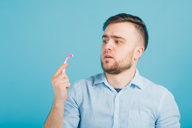 l'uomo barbuto si rade il rasoio rosa su sfondo blu