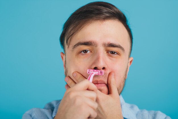 l'uomo barbuto si rade il rasoio rosa su sfondo blu