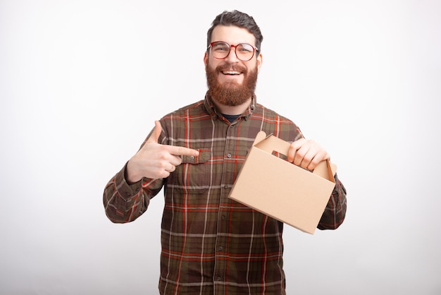 L'uomo barbuto sorridente sta indicando una scatola di consegna che sta tenendo.