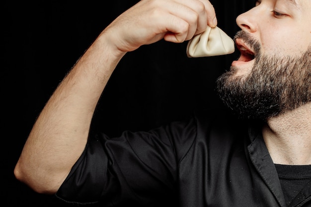 L'uomo barbuto sta mangiando khinkali