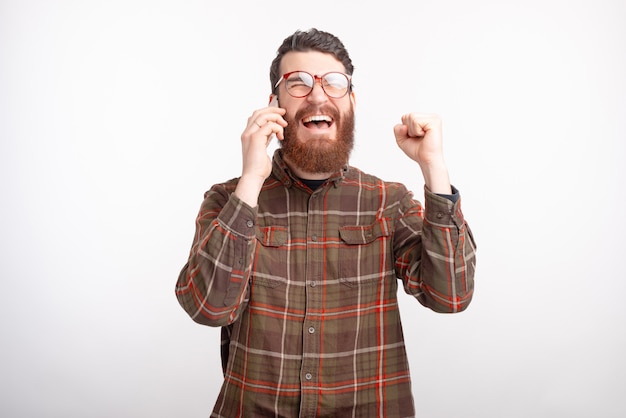 L'uomo barbuto sta parlando al telefono sente alcune buone notizie che fanno il gesto del vincitore.