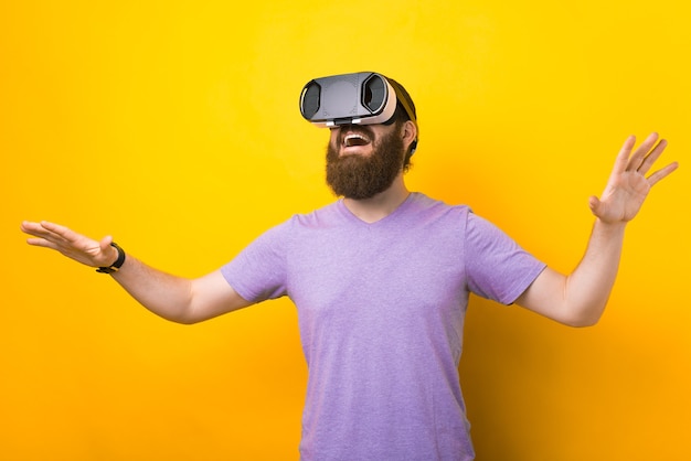 L'uomo barbuto sta provando il suo auricolare VR in uno studio su sfondo giallo.