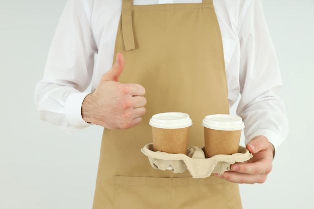 L'uomo barista tiene bicchieri di carta su sfondo chiaro