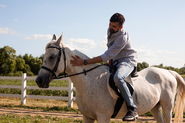 L'uomo bello cavalca un cavallo in un ranch