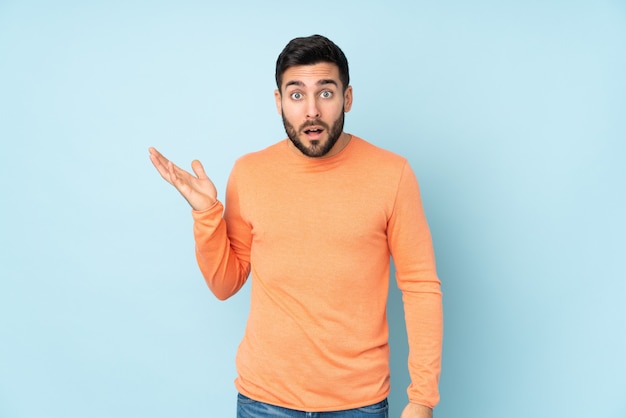 L'uomo bello che fa i dubbi gesturing sopra la parete blu isolata