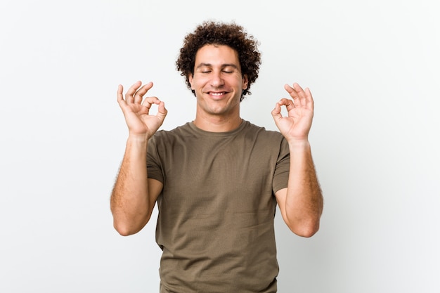 L'uomo bello maturo isolato si rilassa dopo la dura giornata lavorativa, sta eseguendo l'yoga.