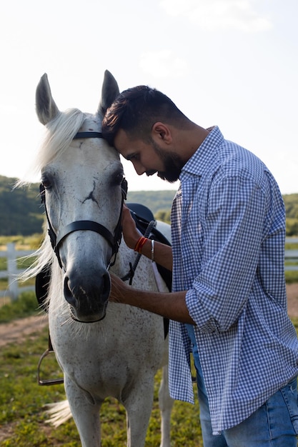 L'uomo bello sta guardando negli occhi di un cavallo