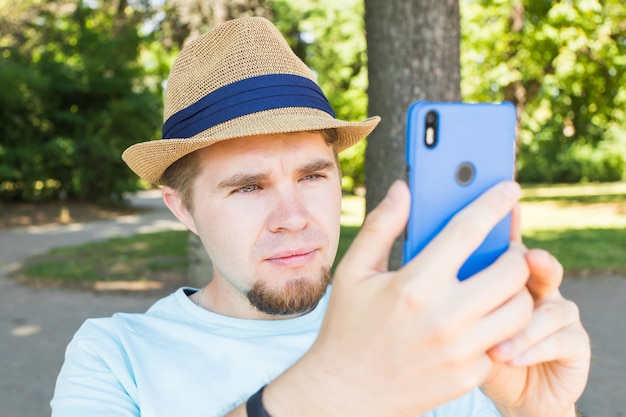 L'uomo bello sta prendendo un selfie all'aperto - persone caucasiche - natura, persone, stile di vita e concetto di tecnologia.