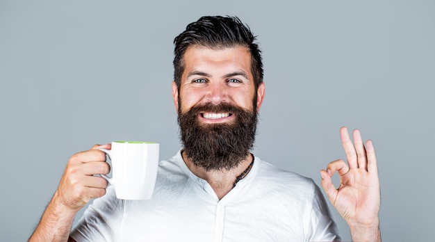 L'uomo bello tiene la tazza di tè del caffè