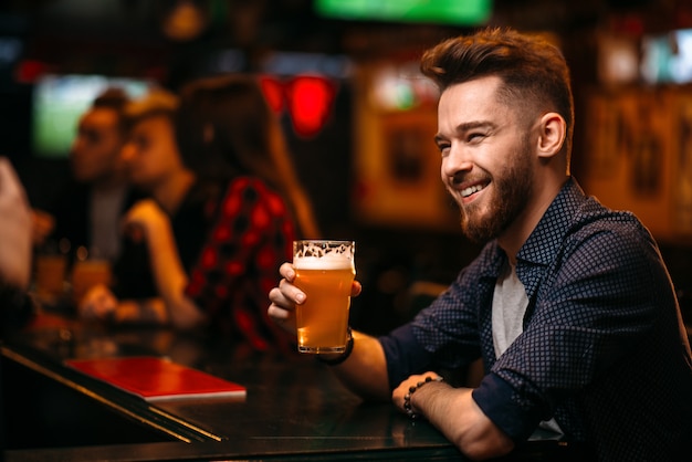 L'uomo beve birra al bancone del bar in un pub sportivo