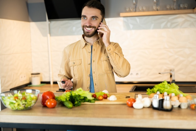 L'uomo bianco con la barba sorride e chiama al telefono in cucina