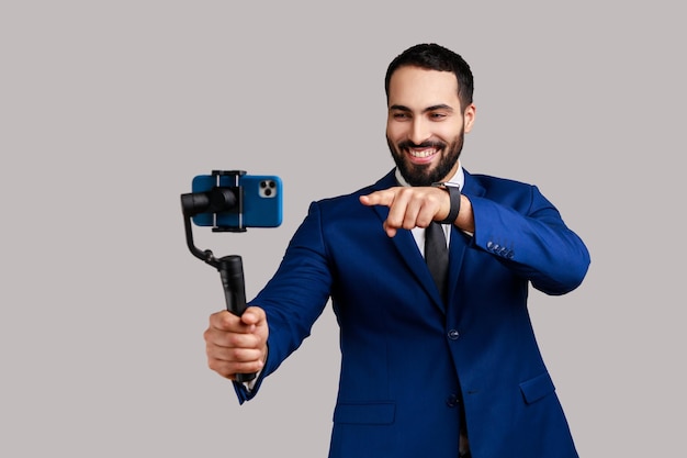 L'uomo blogger tiene in mano una steadicam con il telefono che fa video o ha il livestream che punta alla fotocamera del dispositivo