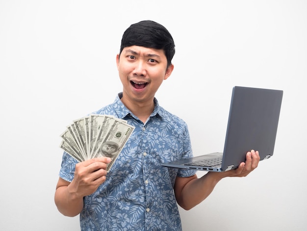 L'uomo blu shrit mostra un sacco di soldi con il laptop in possesso di una sensazione di felicità