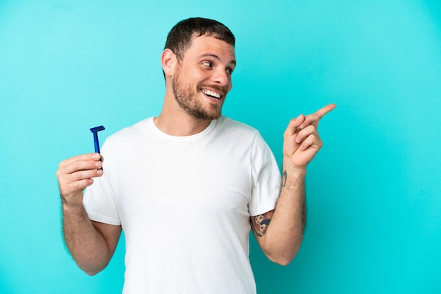 L'uomo brasiliano che si rade la barba isolato su sfondo blu con l'intenzione di realizzare la soluzione sollevando un dito