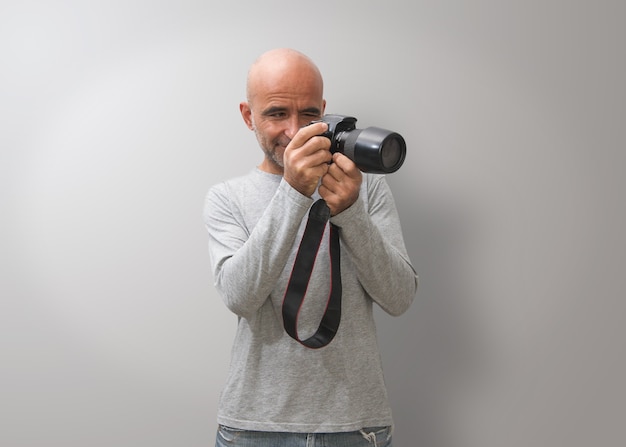 L'uomo calvo attraente manipola una macchina fotografica con i gesti